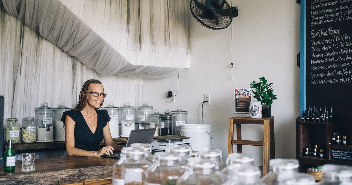 Shop owner working on a laptop at the counter, the admin an AI agent can prepare for her to approve