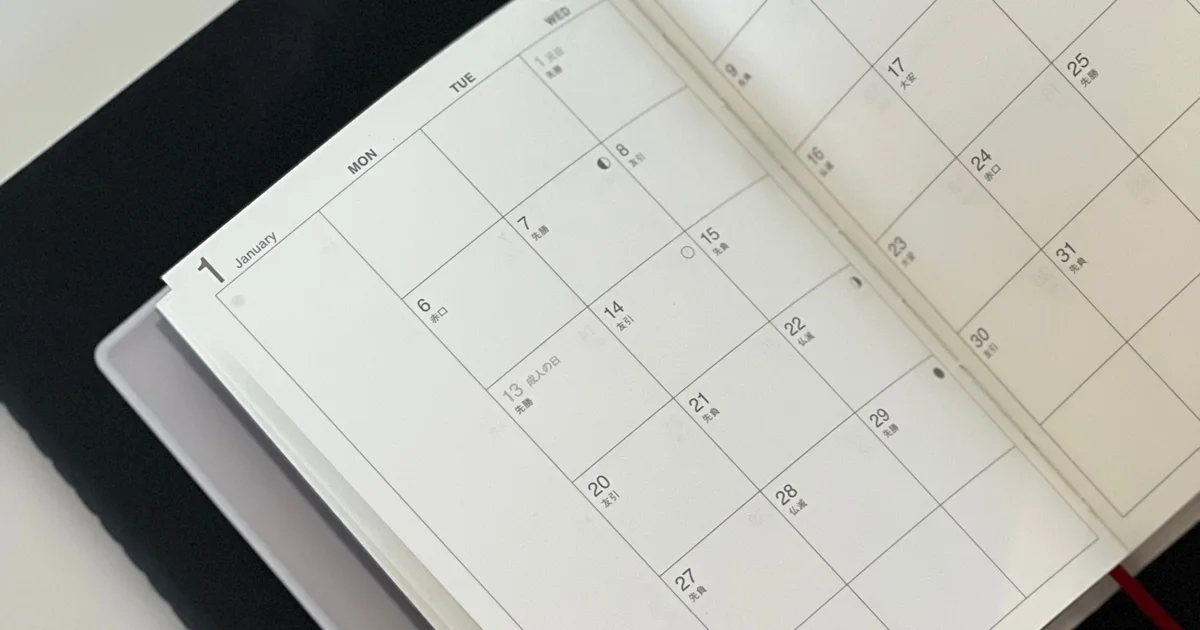 An open monthly planner with empty date boxes on a dark folder