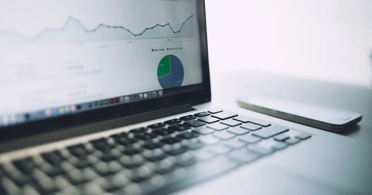 A laptop showing an analytics dashboard with a line chart and a pie chart, next to a smartphone