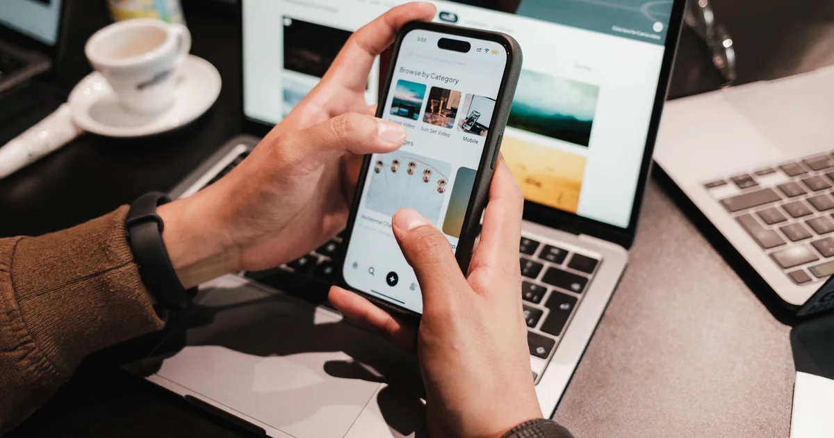 Hands holding a smartphone over a laptop, where a new enquiry gets an instant reply and lands in the follow-up list
