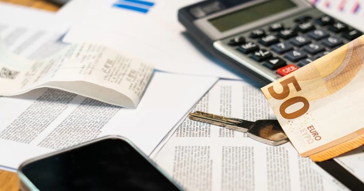 Printed invoices and documents with a calculator, a 50 euro note and a smartphone on a desk