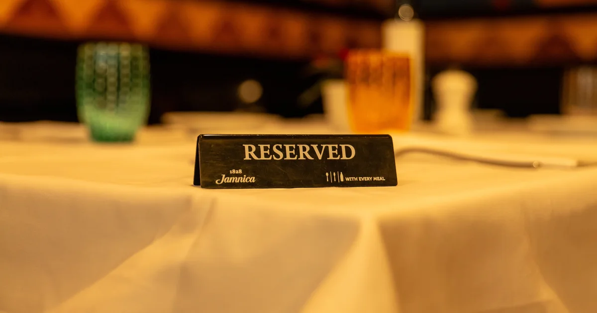 A small black Reserved sign on a white tablecloth in a softly lit restaurant