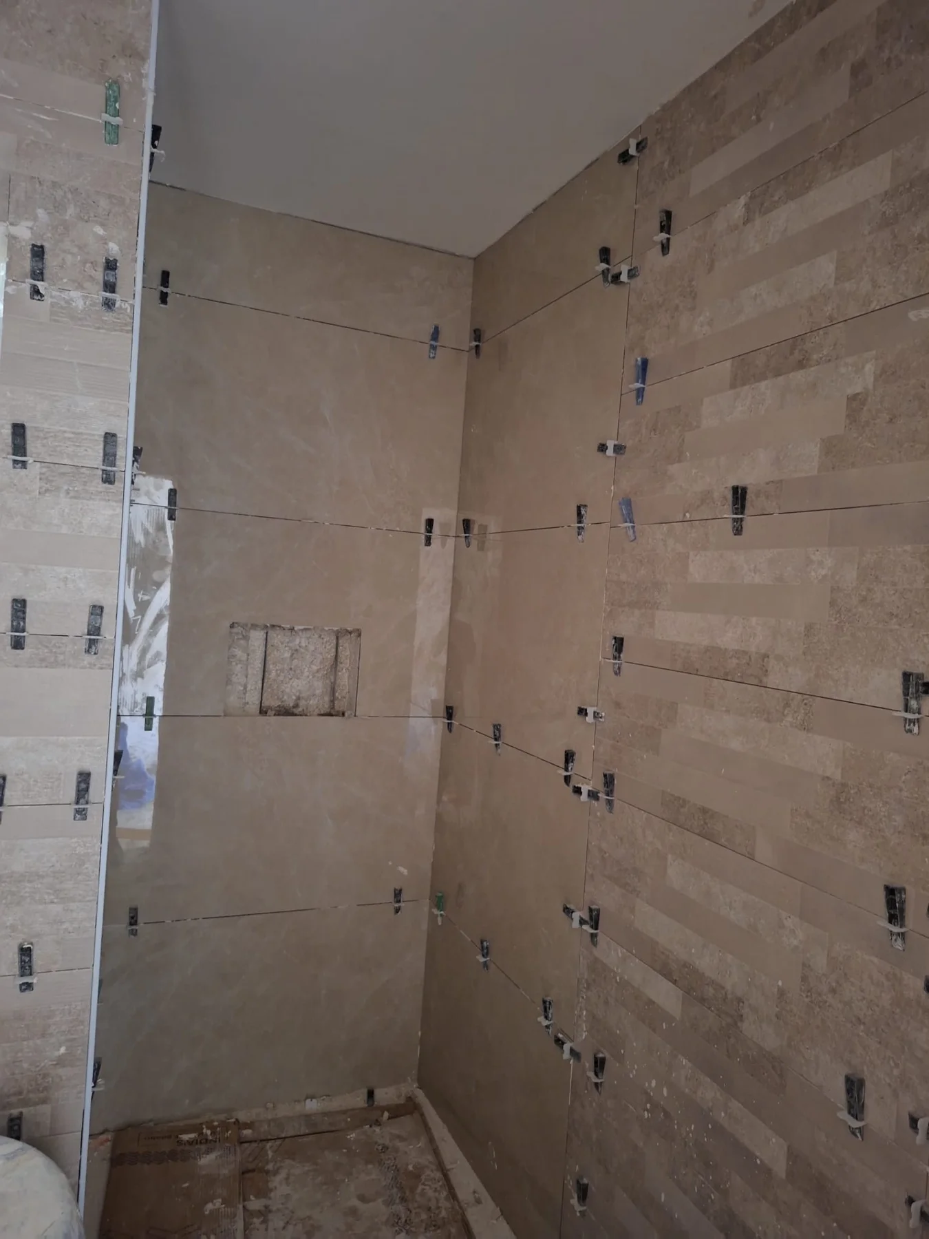 Travertine bathroom wall tiles being set with precision levelling clips