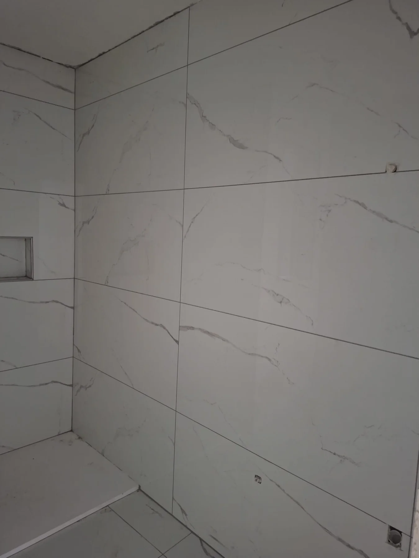 Large white marble-effect porcelain wall tiles in a bathroom wet room